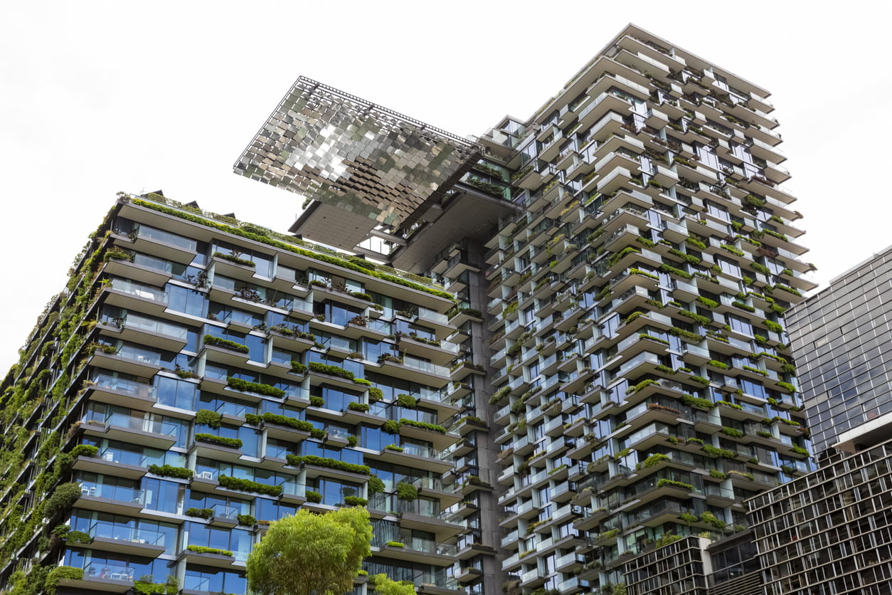 Low angle view of apartment buildings with vertical gardens and heliostat with motorised mirrors, sky background with copy space, Green wall-BioWall or living wall is a wall covered with living plants on residential tower in sunny day, Sydney Australia, full frame horizontal composition