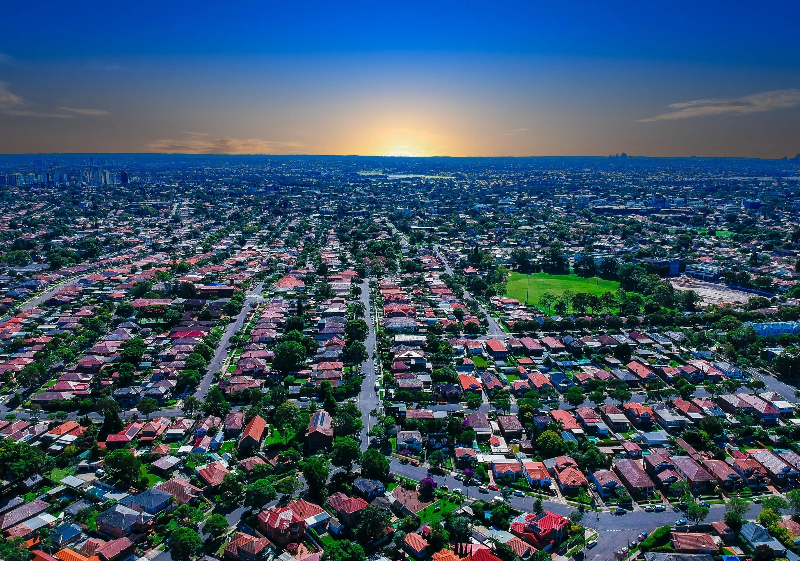 Aerial view of Melbourne suburb, displaying rows of houses with the city in the background as the sun sets. Melbourne is one of the most expensive residential housing markets in Australia, as outlined in the June 2025 economic update.